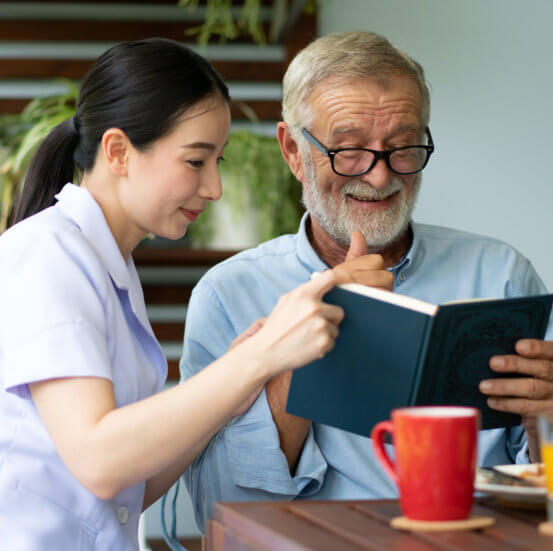 Caregiver and elderly reading book