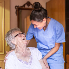 Elderly woman and caregiver smiling at each other